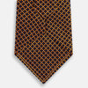 View 3 of product The Turnbull & Asser Orange and Navy Diamond Silk Tie features a yellow and orange diamond pattern on navy silk, ideal for modern office attire, and is displayed rolled up on a light surface.