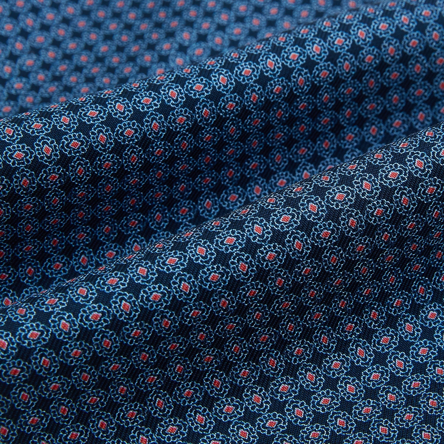 View 4 of product The Turnbull & Asser Navy and Red Rosette Cravat is adorned with a repeating geometric pattern of red, white, and light blue circles—an ideal formal accessory displayed against a white background.