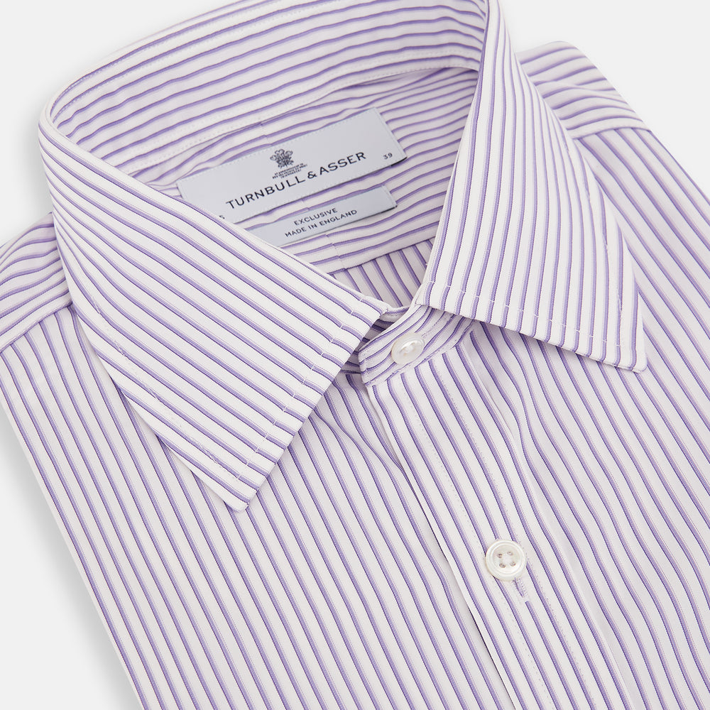The Turnbull & Asser Purple Shadow Stripe Mayfair Shirt features a long-sleeve button-up design with thin vertical blue and white stripes, a T&A collar, and buttoned cuffs, shown on a plain white background.