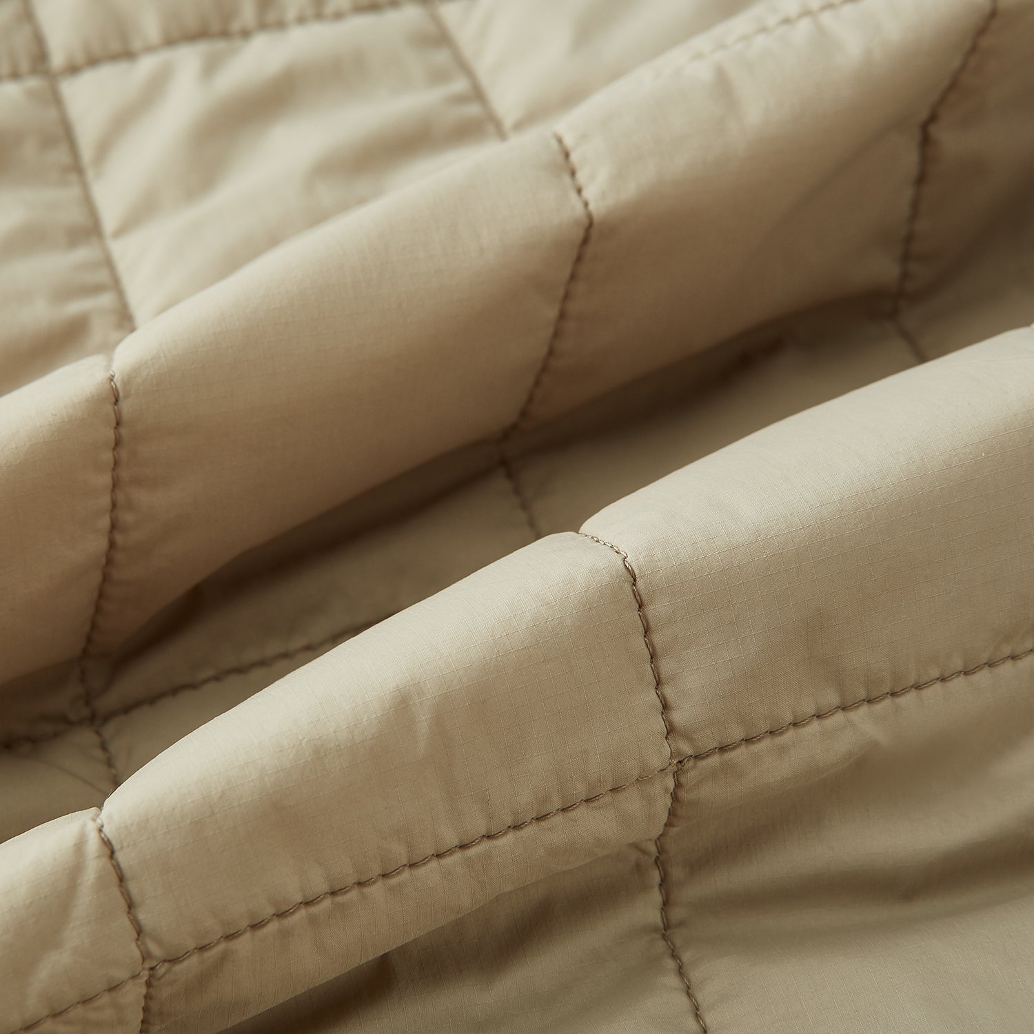 View 4 of product The Turnbull & Asser Sand Quilted Gilet is a beige, lightweight vest featuring a front zipper, two zippered side pockets, a chest pocket, and a rounded hem, shown against a white background.