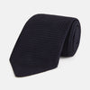 View 1 of product The GRENADINE NAVY TIE by Turnbull & Asser—a rolled, dark navy blue textured tie—serves as an essential accessory for smart outfits, shown against a plain white background.
