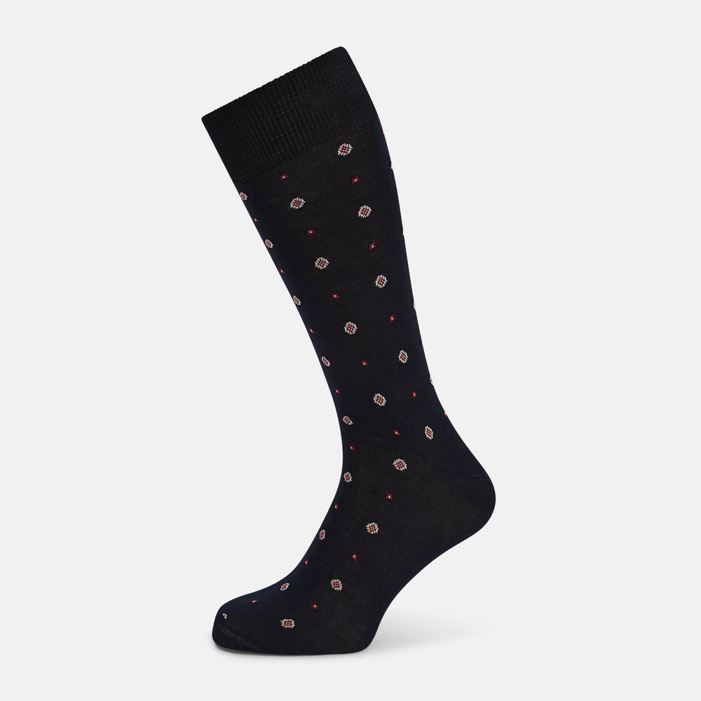 The Turnbull & Asser Midnight Patterned Mid-Length Sock features a ribbed cuff and a design of small white hexagons with red dots, shown here as a single sock on a plain white background.