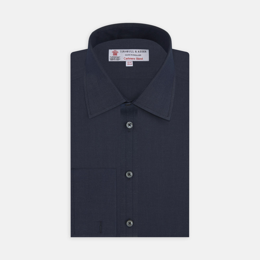 A neatly folded Turnbull & Asser Dark Blue Denim-Cashmere Shirt with a T&A collar and double cuffs, featuring black buttons, shown on a white background. The label inside the collar highlights its smart finish and refined style.