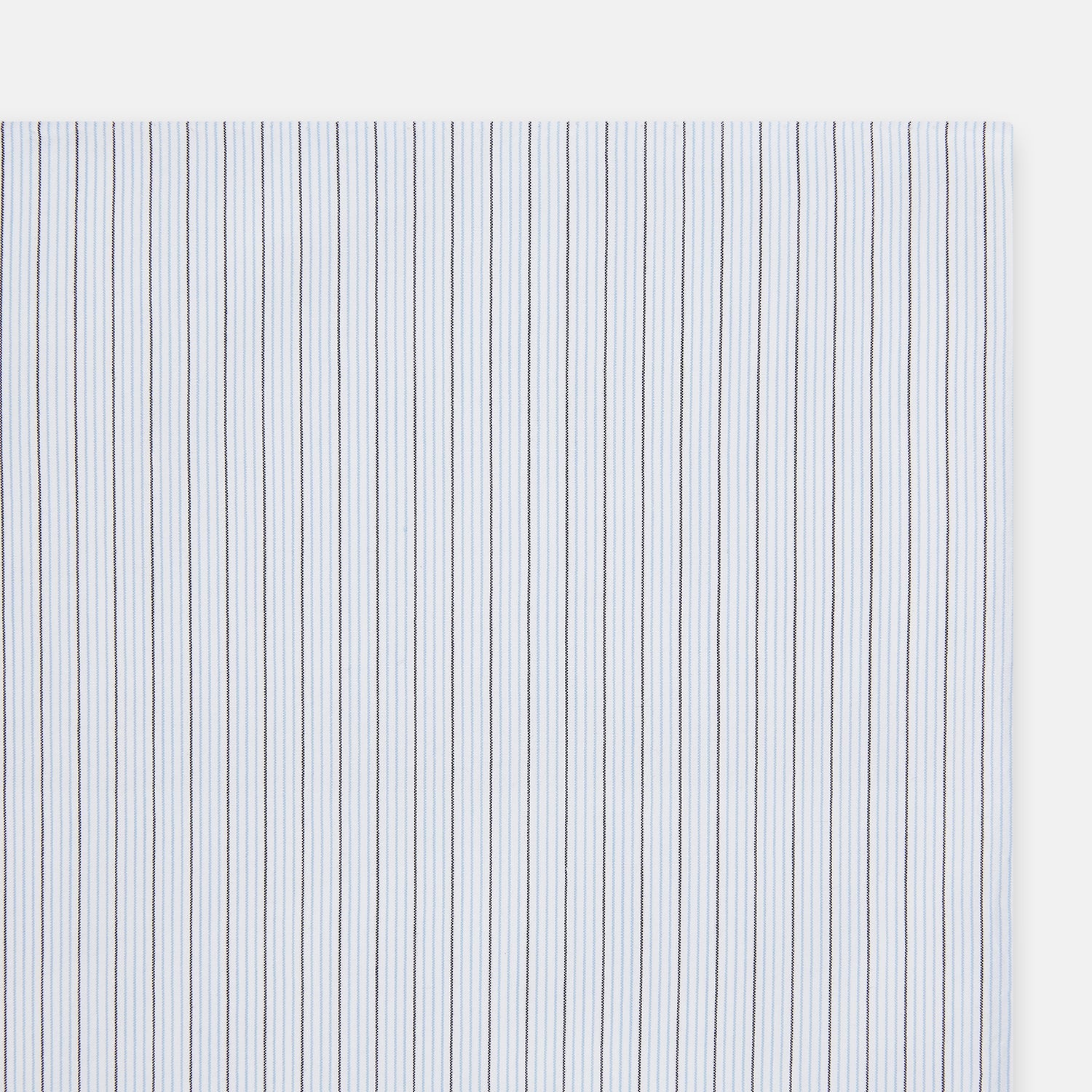 View 2 of product The Turnbull & Asser Hand Rolled Blue Multi Stripe Handkerchief features light blue cotton with thin black and white stripes, making it a refined accessory for the gentleman.