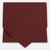 View 1 of product The Great Gatsby Burgundy Printed Silk Cravat by Turnbull & Asser features a maroon silk fabric with a small yellow and blue geometric pattern, subtle sheen, and neatly finished edges for an elegant, Gatsby-inspired formal accessory.
