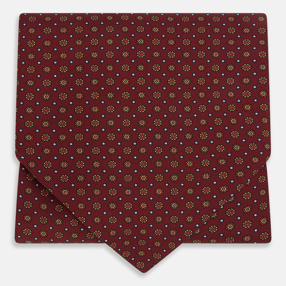 The Great Gatsby Burgundy Printed Silk Cravat by Turnbull & Asser features a maroon silk fabric with a small yellow and blue geometric pattern, subtle sheen, and neatly finished edges for an elegant, Gatsby-inspired formal accessory.
