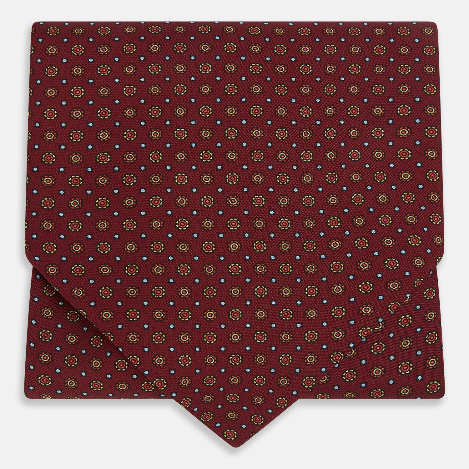 View 1 of product The Great Gatsby Burgundy Printed Silk Cravat by Turnbull & Asser features a maroon silk fabric with a small yellow and blue geometric pattern, subtle sheen, and neatly finished edges for an elegant, Gatsby-inspired formal accessory.
