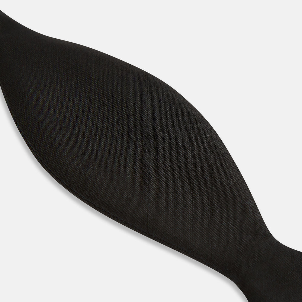 The Casino Royale Shantung Silk Bow Tie by Turnbull & Asser, as seen on James Bond, features a classic shape in black silk and is set against a plain white background—a timeless gentleman’s accessory.