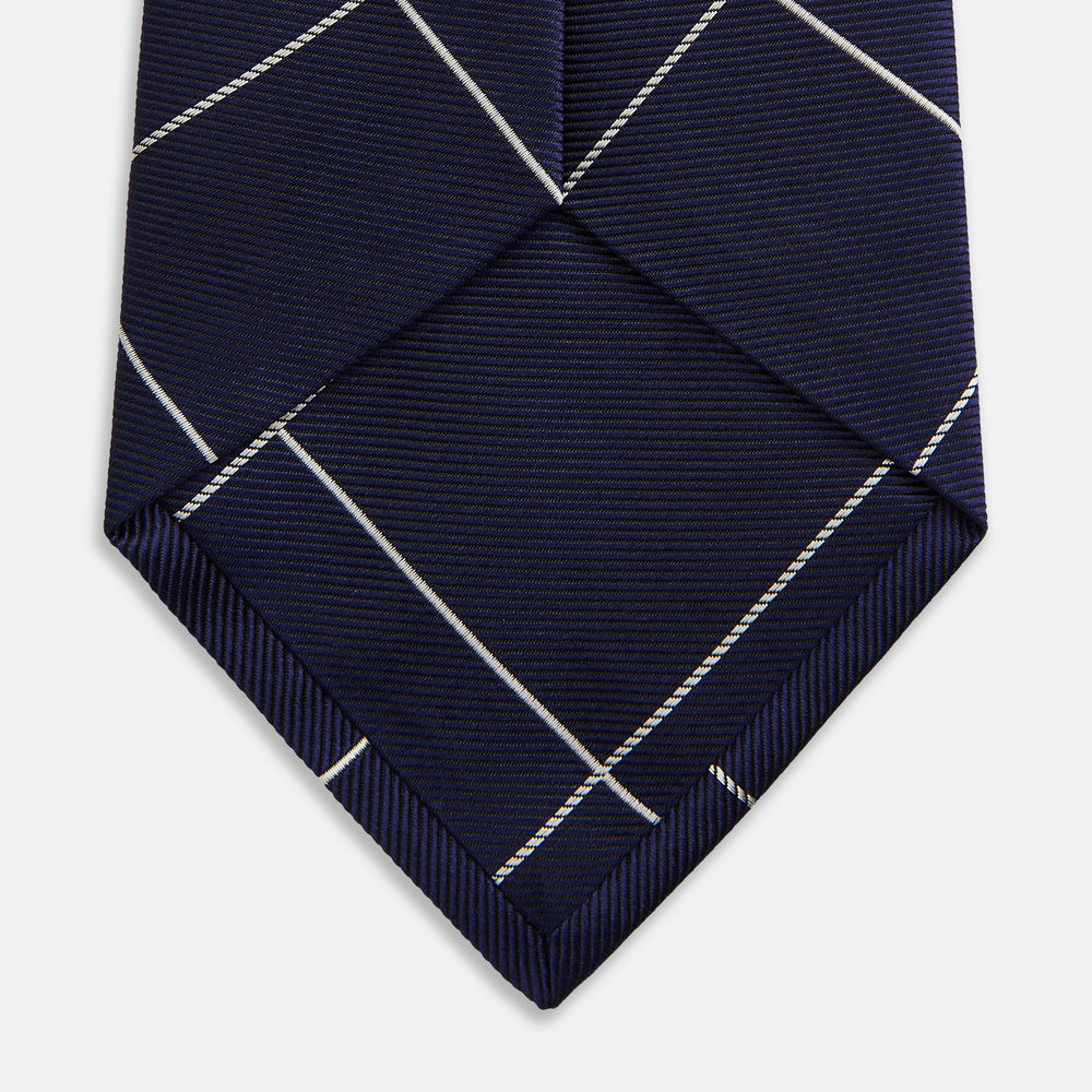 The Turnbull & Asser WINDOW PANE NAVY WHITE TIE features navy blue silk with a subtle diagonal ribbed texture and white windowpane checks, making it the perfect men’s accessory for any formal occasion.