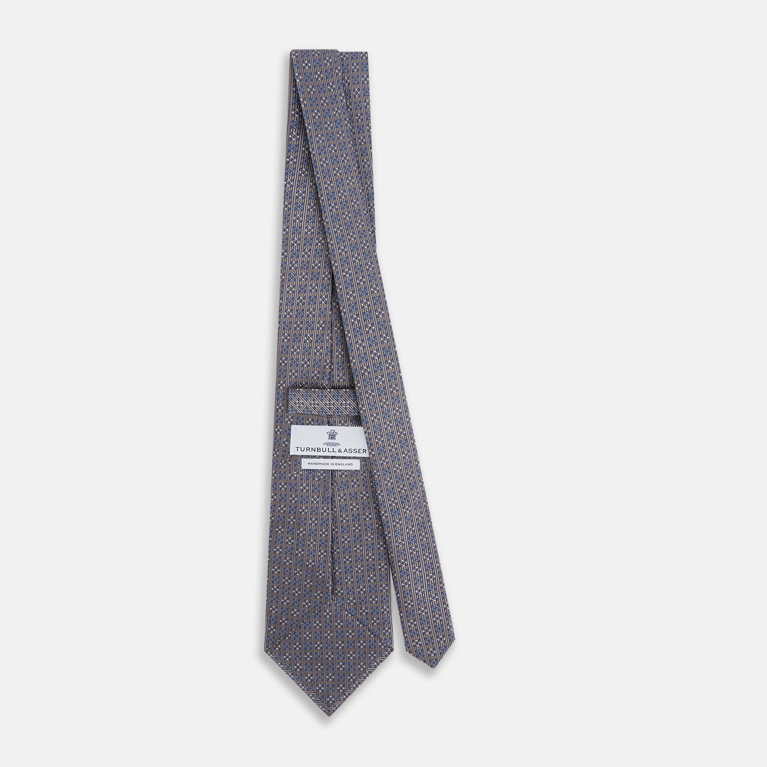 View 4 of product The Turnbull & Asser Silver and Pale Blue Multi Dot Silk Tie features elegant small dots on light brown silk, ideal for modern office wear, shown rolled up against a white background.
