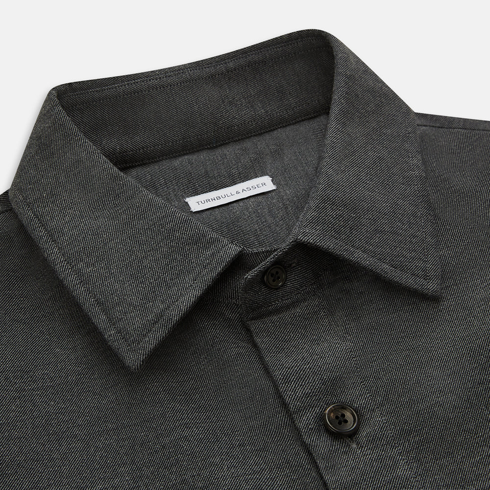 The Charcoal Melange Hampstead overshirt by Turnbull & Asser is a dark gray long-sleeve button-up with a collar, left chest pocket, and two zippered side pockets, shown laid flat on a white background.