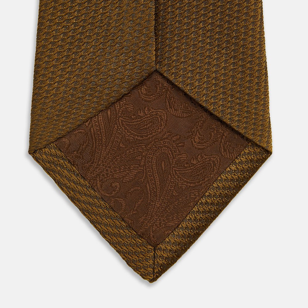 The Turnbull & Asser Plain Lace Jacquard Earth Tie, an essential brown wardrobe accessory, is shown rolled up against a plain white background.