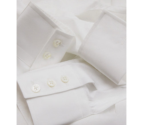 Close-up of the cuffs of a neatly folded white dress shirt, showing white buttons and crisp fabric texture.