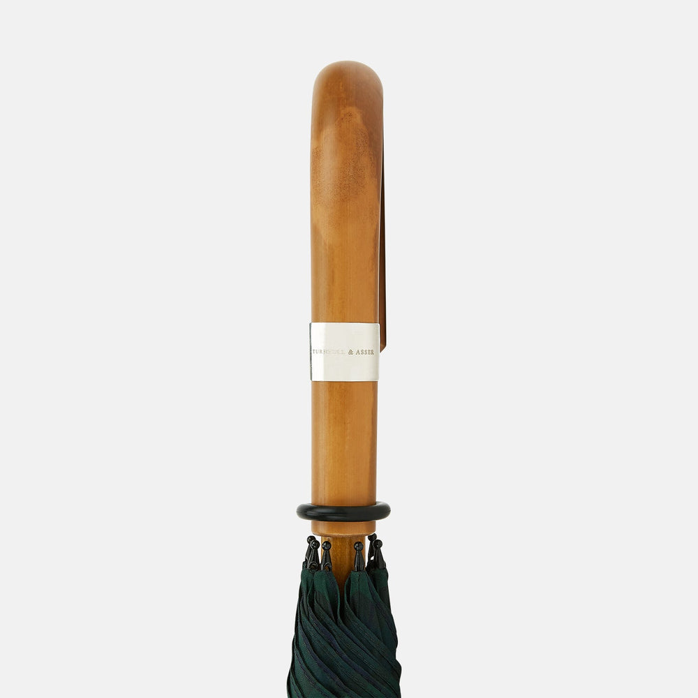 The Turnbull & Asser Black Watch Tartan Traveller Umbrella features a Malacca crook handle and a dark green and navy blue plaid canopy, shown against a plain white background.