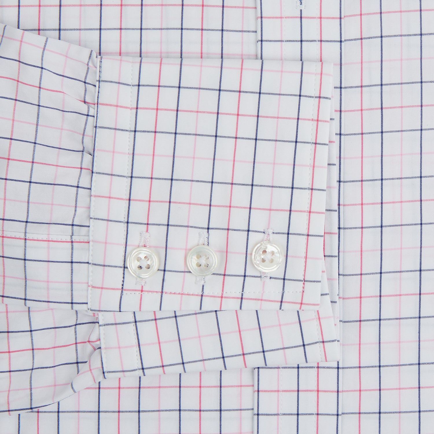 View 4 of product The Turnbull & Asser Pink Overlay Grid Check Mayfair Shirt is a long-sleeved, button-up with a collar and buttoned cuffs, featuring a white base and thin pink grid lines. Laid flat against a white surface.