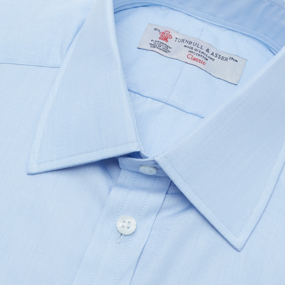 The Turnbull & Asser Light Blue End-on-End Shirt features a T&A collar and 3-button cuffs, neatly displayed against a plain white background—ideal for pairing with a navy suit.