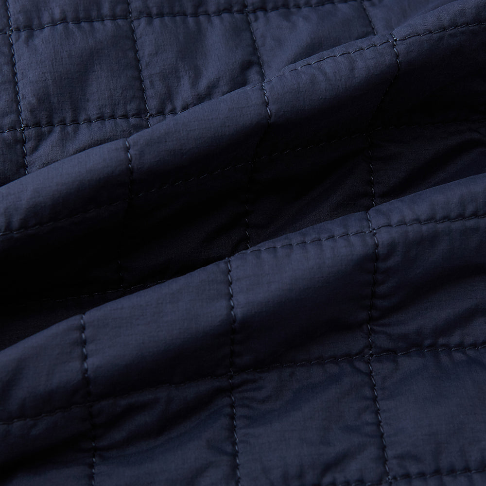 The Turnbull & Asser Navy Double-Breasted Quilted Gilet is a sleeveless piece with an asymmetrical button closure, chest pocket, and two zippered side pockets, shown on a plain white background—ideal for layered dressing.