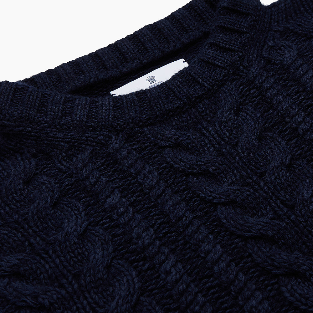 The Turnbull & Asser Navy Wool and Cotton Blend Albany Guernsey Jumper, shown flat on a white background, features long sleeves, a classic cable knit pattern on the upper half, and ribbed cuffs, hem, and collar.