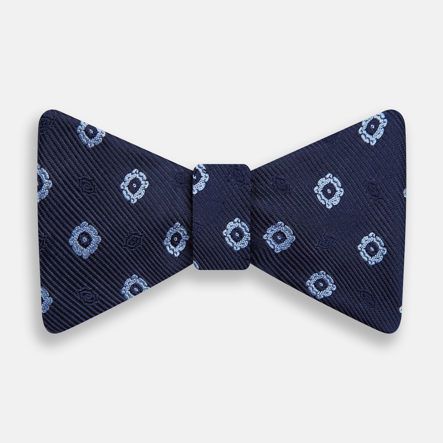 View 1 of product The Navy and Sky Blue Motif Silk Bow Tie by Turnbull & Asser features a subtle ribbed texture and light blue and white geometric floral patterns—an elegant choice for formalwear.