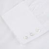 View 4 of product The Sea Island Cotton Classic Fit White Shirt by Turnbull & Asser features a classic collar and front buttons, neatly folded with its label visible, displayed on a light blue background.