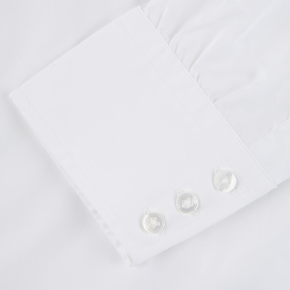 The Sea Island Cotton Classic Fit White Shirt by Turnbull & Asser features a classic collar and front buttons, neatly folded with its label visible, displayed on a light blue background.