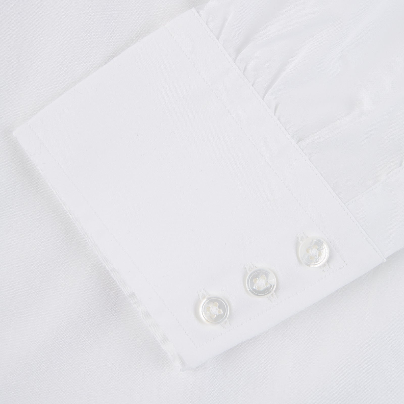 View 4 of product The Sea Island Cotton Classic Fit White Shirt by Turnbull & Asser features a classic collar and front buttons, neatly folded with its label visible, displayed on a light blue background.
