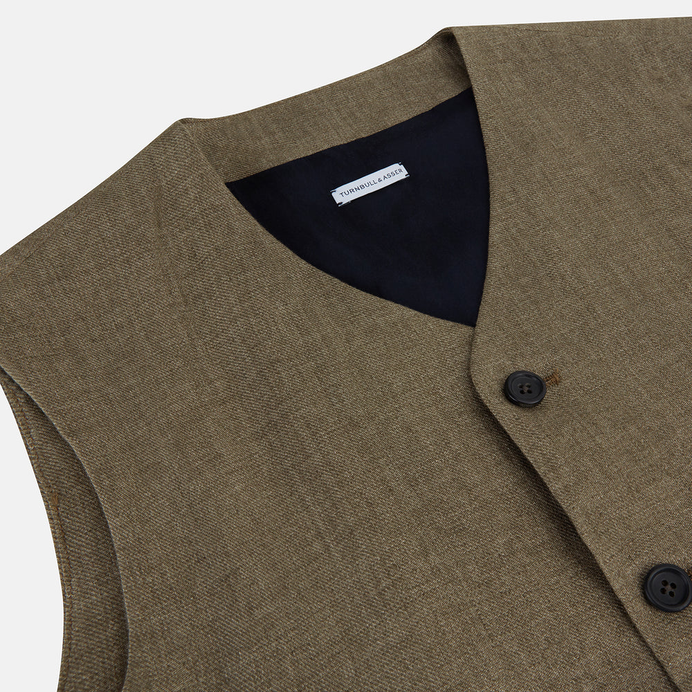 An olive, sleeveless linen twill waistcoat by Turnbull & Asser with a V-neck, five black buttons, two slanted zippered pockets, and a chest pocket, shown against a plain white background.