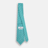 View 4 of product The Turnbull & Asser Turquoise Flower Patterned Silk Tie, featuring small white flowers, is shown rolled up on a white background.