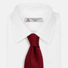 View 2 of product The Turnbull & Asser Plain Herringbone Burgundy Tie features a subtle pattern and rich color, making it an essential accessory for smart attire. Neatly rolled, it’s elegantly displayed on a plain white background.