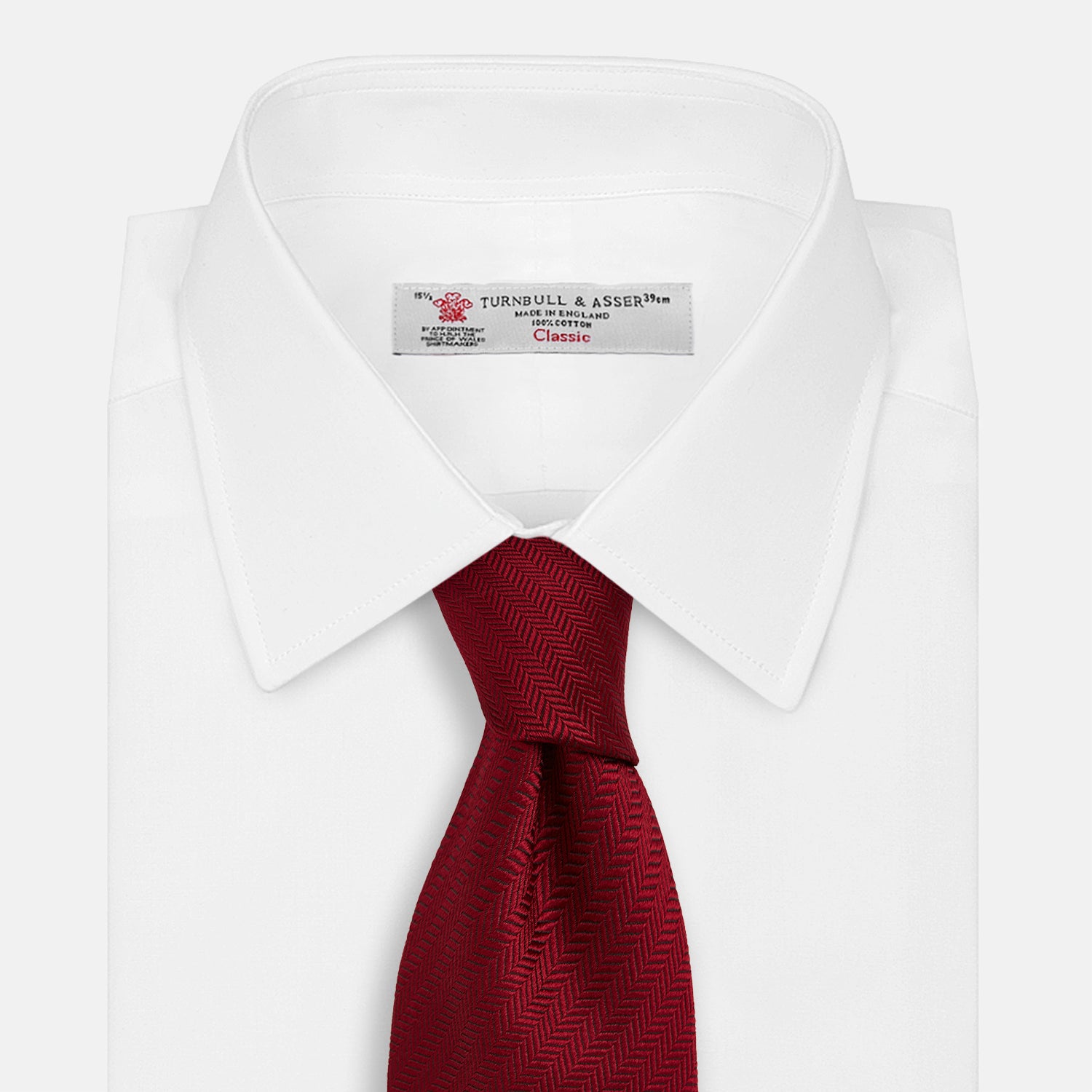 View 2 of product The Turnbull & Asser Plain Herringbone Burgundy Tie features a subtle pattern and rich color, making it an essential accessory for smart attire. Neatly rolled, it’s elegantly displayed on a plain white background.