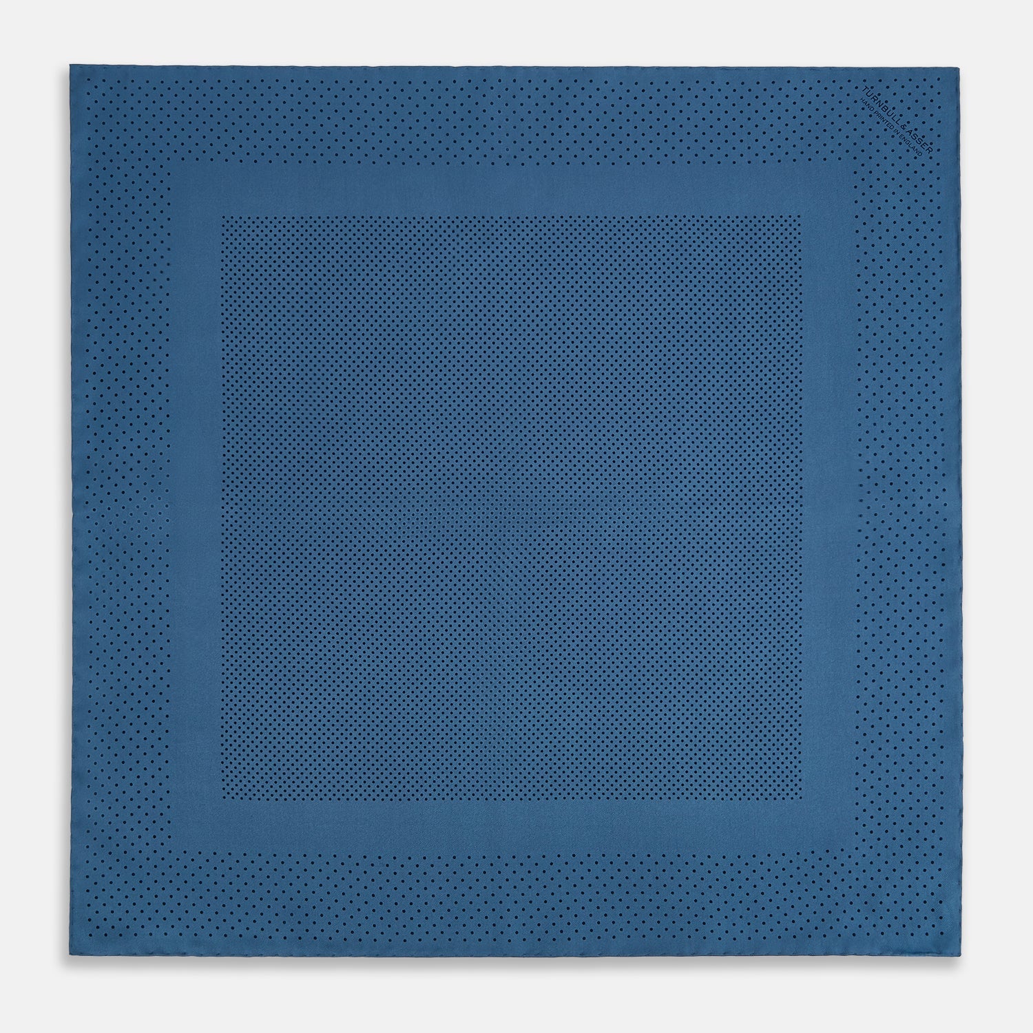 View 4 of product The Blue Dot Silk Pocket Square by Turnbull & Asser features small black polka dots on blue silk and is made in England. The image shows it neatly folded, with a corner turned down to display both sides.