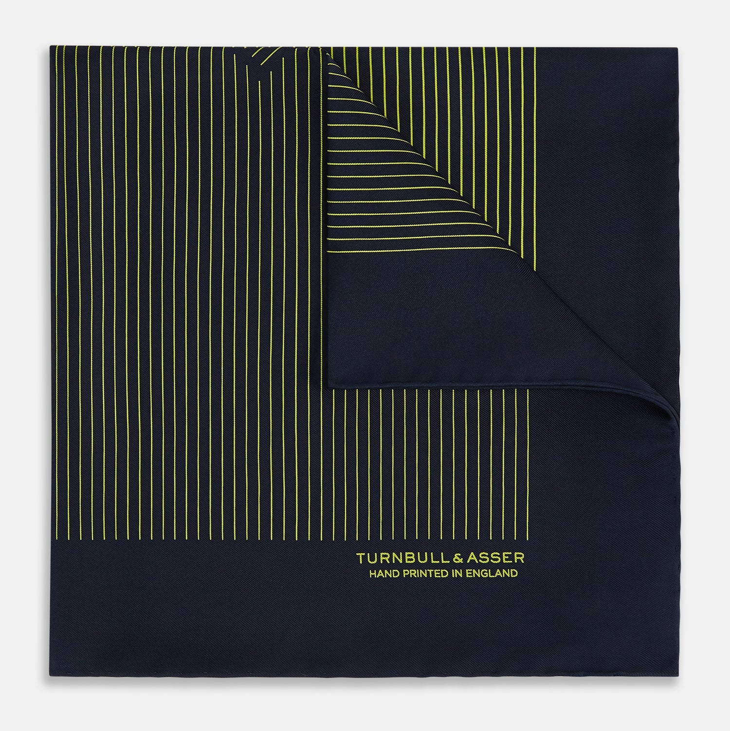 View 1 of product Turnbull & Asser Navy and Yellow Stripe Silk Pocket Square features hand-rolled edges, striped pattern, and "Turnbull & Asser Hand Printed in England" text in yellow on the bottom right corner.