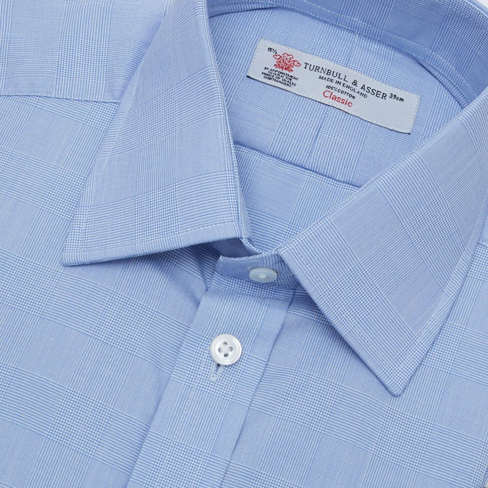A Blue Prince of Wales Check Shirt by Turnbull & Asser, featuring a T&A collar and 3-button cuffs, is neatly folded and displayed on a plain white background.