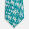 View 3 of product The Turnbull & Asser Turquoise Flower Patterned Silk Tie, featuring small white flowers, is shown rolled up on a white background.