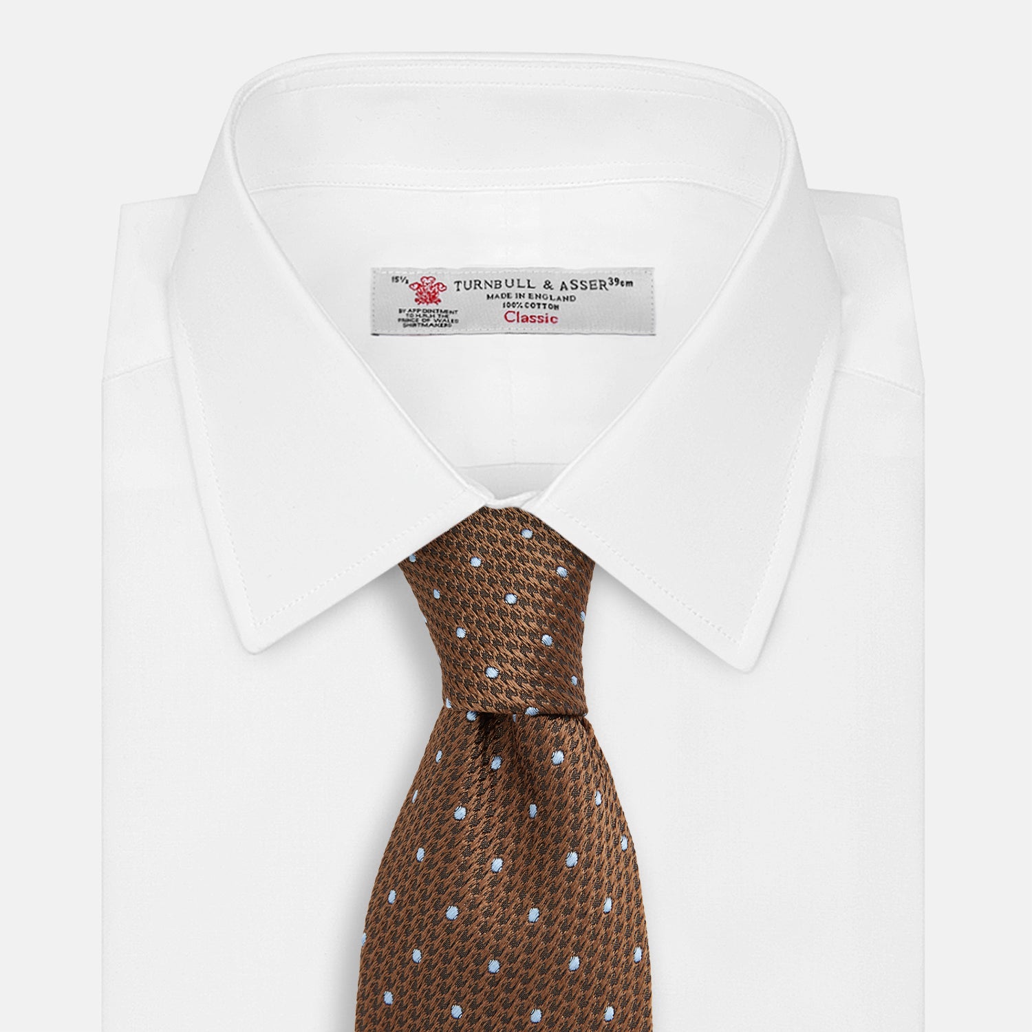 View 3 of product The LACE ON TONE SPOT EARTH RIVER TIE by Turnbull & Asser is a brown woven tie with small light blue dots, shown rolled up on a white background—a stylish accessory for formal outfits.