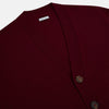 View 2 of product The Turnbull & Asser Burgundy Cashmere Cardigan features a V-neck, ribbed cuffs and hem, two front pockets, and a classic button-up design, shown on a plain white background.