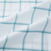 View 6 of product The Turnbull & Asser Sage Grid Check Mayfair Shirt is a white, long-sleeve shirt made from Italian cotton with a light blue and sage grid pattern, shown neatly laid flat on a plain, light background.