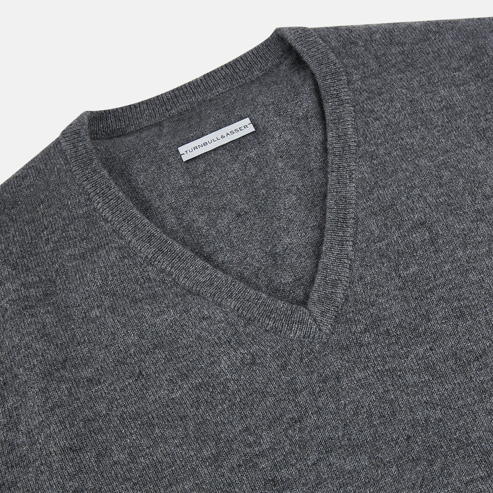 The Turnbull & Asser Storm Grey Cashmere V-neck Jumper features long sleeves, ribbed cuffs and hem—versatile knitwear shown on a white backdrop.