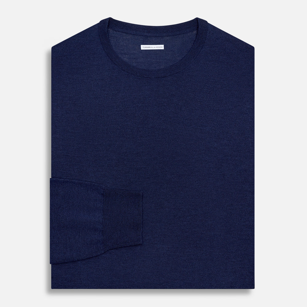 The Turnbull & Asser Navy Merino Round Neck Jumper is shown against a light gray background, featuring a classic long-sleeve design with ribbed cuffs, hem, and neckline for timeless style.