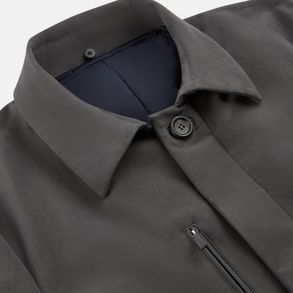 The Turnbull & Asser Charcoal Melange John Arthur Trench Coat, featuring a collar, single-breasted closure, and three zippered pockets—one chest and two at the hips—is shown against a plain white background.
