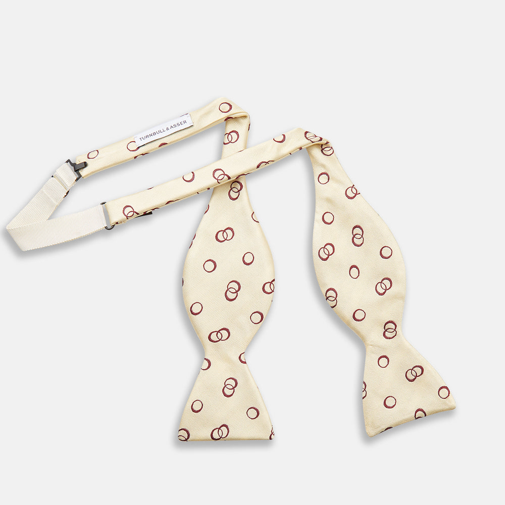 The Yellow Geometric Rings Silk Bow Tie by Turnbull & Asser features interlocking rings in a bold geometric pattern, crafted from silk.