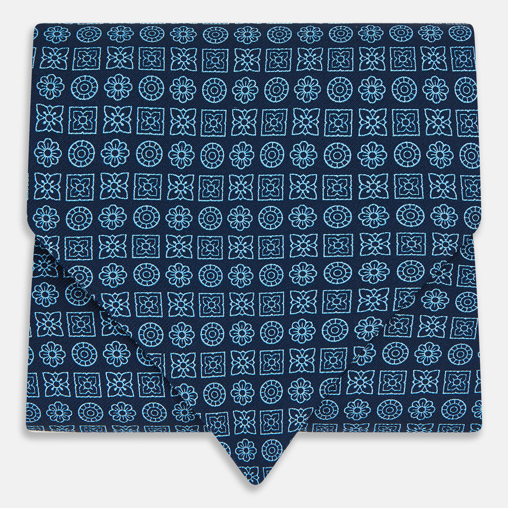 The Turnbull & Asser Dark Navy Floral Tile Pattern Printed Silk Cravat features a British-inspired light blue floral tile design, elegantly displayed on a white background.