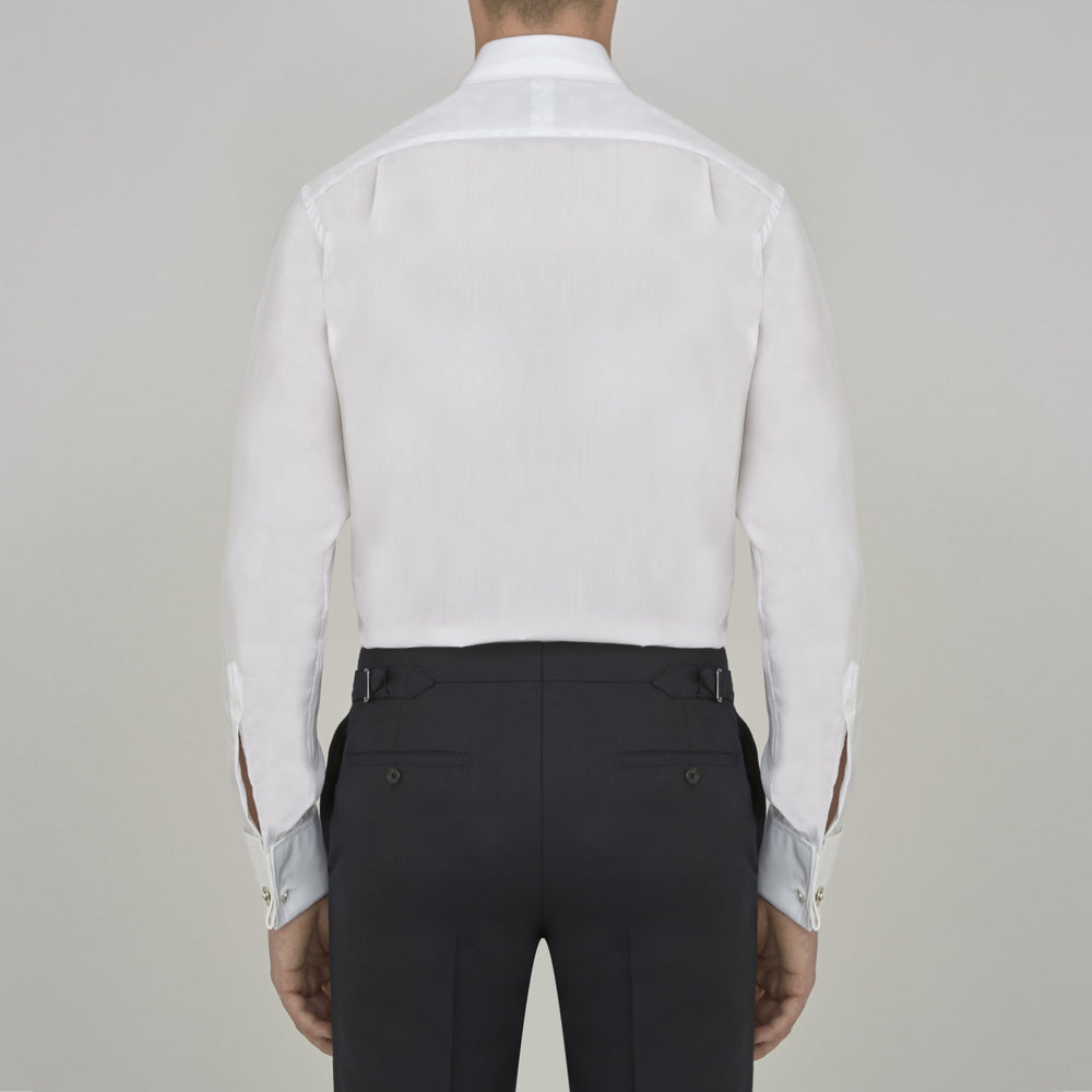 A Turnbull & Asser Two-Fold 200 White Cotton Shirt with T&A collar and double cuffs, neatly folded to show the label inside the collar, is displayed on a light blue background.