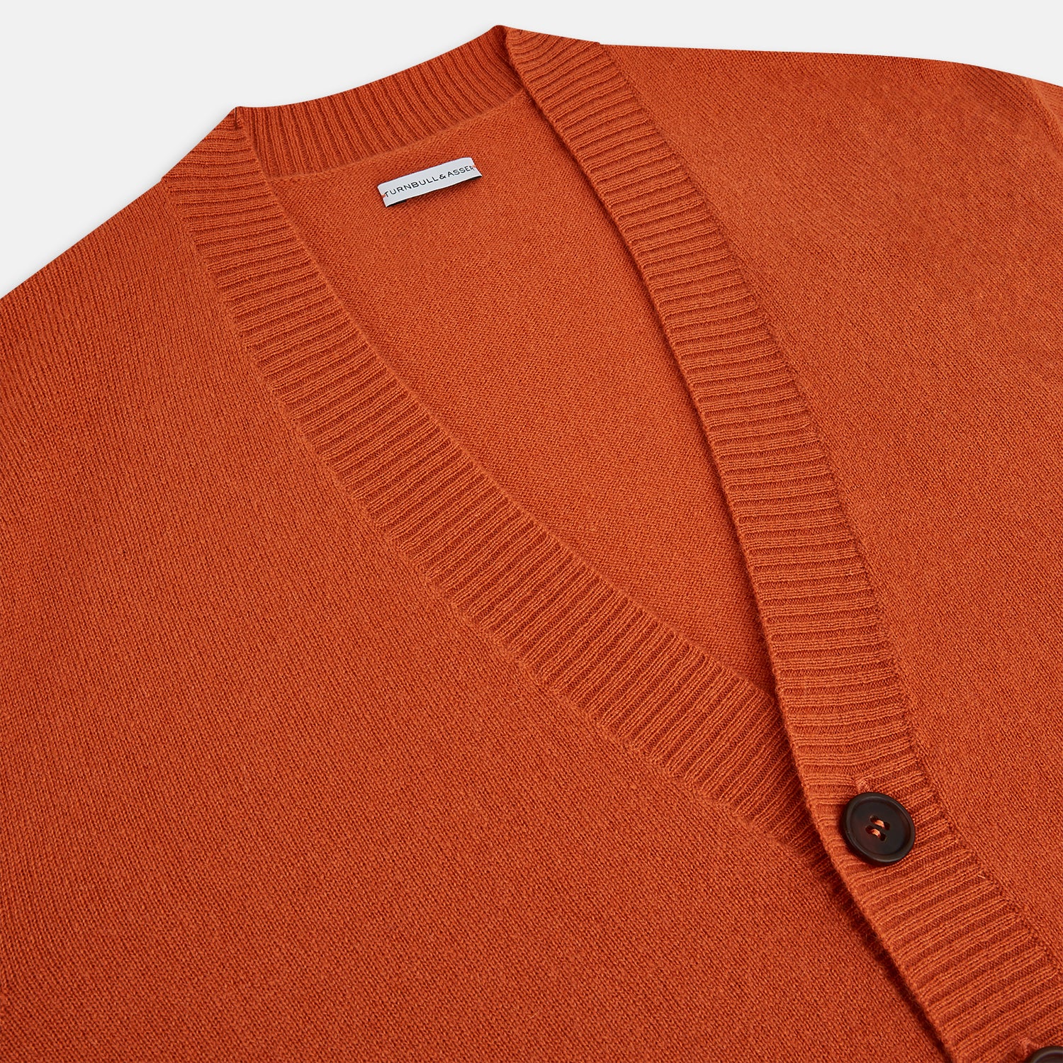 View 2 of product The Orange Cashmere Cardigan by Turnbull & Asser showcases vibrant burnt orange, a V-neck, dark buttons, ribbed cuffs and hem, long sleeves, and two front pockets. Part of the knitwear collection; displayed on a white background.