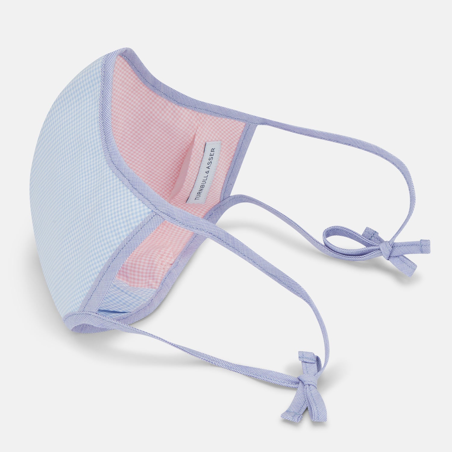 View 4 of product The Turnbull & Asser Pink & Blue Check Commuter Mask features lavender adjustable ear loops tied in bows and comes with 3 Viroformula™ filters. Shown on a plain white background.