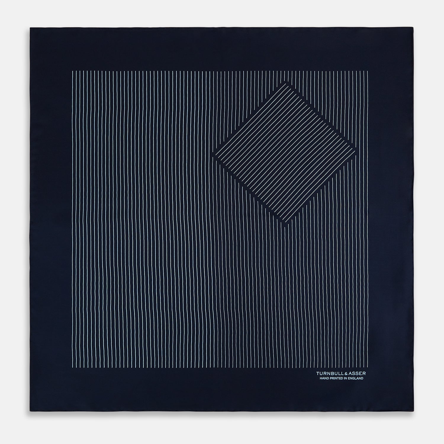 View 3 of product The Turnbull & Asser Navy and Light Blue Stripe Silk Pocket Square features hand-rolled edges and "Turnbull & Asser Hand Printed in England" in white text.
