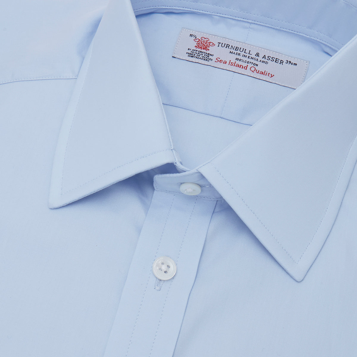 View 2 of product The Turnbull & Asser Light Blue Sea Island Quality Cotton Shirt features a T&A collar, double cuffs, white buttons, and a quality label inside the collar. Displayed on a plain white background.