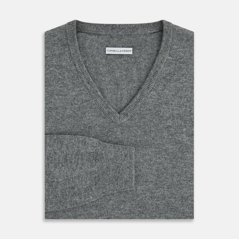 The Turnbull & Asser Grey Melange Cashmere V-neck Jumper features long sleeves, ribbed cuffs and hem, showcasing timeless style against a white background.