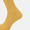 View 4 of product The Turnbull & Asser Banana Long Socks are knee-high, golden-yellow, and made from mercerised Egyptian cotton, shown upright on a white background to highlight their ribbed texture and fitted shape.
