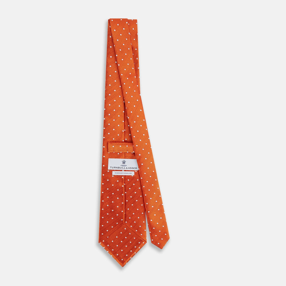 The Turnbull & Asser Orange and White Micro Dot Silk Tie features a subtle herringbone weave with small white dots—an elegant, modern accessory for the office.